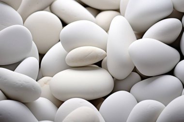 Pürüzsüz yüzeyleri olan el değmemiş, beyaz nehir taşlarına yakın çekim. Bu zen benzeri doku, kaplıca ve sağlık temalarının yanı sıra modern sağlık temaları için temiz ve doğal bir arka plan sunar....