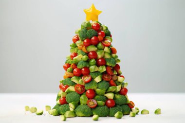 Taze brokoli, kiraz domatesleri ve diğer canlı sebzelerden yapılmış eşsiz, şenlikli bir Noel ağacı süsü. Bayram temalı mutfak kreasyonları, sağlıklı beslenme içeriği ve sanatsal vejetaryen görselleri için mükemmel..