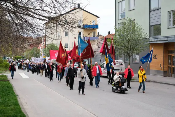 Nynashamn, İsveç - Mayıs 12025: İsveç, AB, BM ve kırmızı bayraklarla yürüyüş yapan 1 Mayıs göstericileri. Protestocular sosyal reform ve işçi hakları talep ediyorlar.