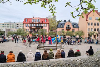 Nynashamn, İsveç - Mayıs 12025: Kasaba meydanında düzenlenen 1 Mayıs etkinliği sırasında seyirci hoparlörü. Kürsünün etrafında kırmızı, İsveç ve AB bayrakları bulunan insanlar.