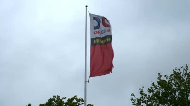 Nynashamn, Stockholm İlçesi, İsveç - 30 Mayıs 2025 OKQ8 benzin istasyonu bayrağı bulutlu bulutlarla rüzgarda dalgalanıyor