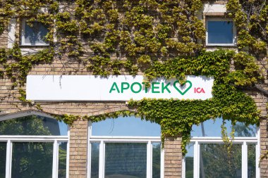 Nynashamn, Stockholm İlçesi, İsveç - 19 Mayıs 2025: Üzerinde sarmaşık büyüyen bir bina ve Apotek yazan bir tabela. Bina tuğladan yapılmıştır..