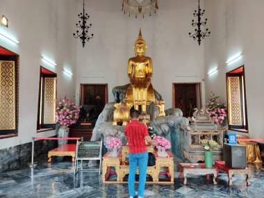 Tayland 'ın Budist Tapınağında Altın Buda heykelinin önünde dua eden adam.