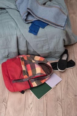 Bir çift çocuk ayakkabısı, dağınık kitaplar ve odanın zemininde kırmızı renkli bir sırt çantası var. Temizlik ve disiplin. Dökülüyor