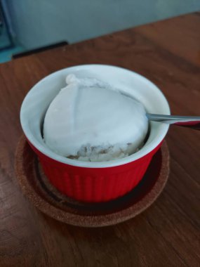 Tahta bir yüzey üzerinde kaşıkla bir kase pirincin yakın çekim görüntüsü.