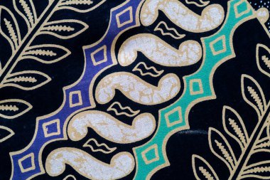 Batik kumaşın ayrıntılı bir görünümü siyah, mavi ve yeşil renkli geometrik desenler içerir..