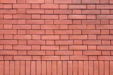 Ufuk çizgileri ve altta dikey tuğla deseni olan dokulu kırmızı tuğla bir duvarın yakın çekimi.
