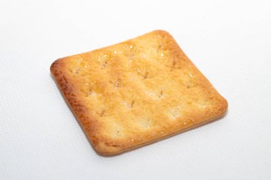 Tek altın esmer şekerli kraker, kare şeklinde, beyaz arka planda yumuşak bir gölge bırakıyor..