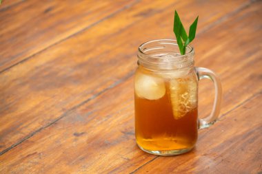 Pandan yaprağı garnitürlü mason kavanozunda buzlu çay. Ahşap masa arkaplanı.