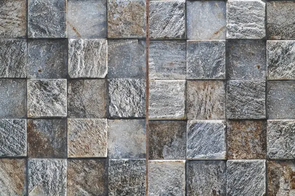 Kare kareyle kaplanmış yüzey, gri ve kahverenginin değişik tonlarında desenli taşlar, mozaik benzeri bir desen yaratıyor..