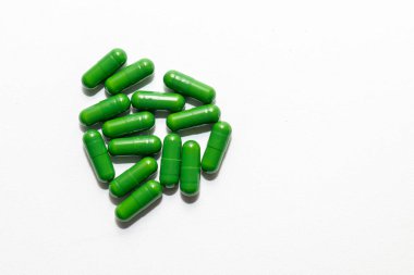 Parlak yeşil kapsüllerden oluşan bir küme, temiz beyaz bir arkaplan üzerine dizilmiş..