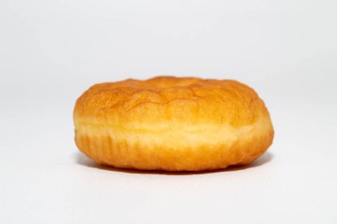 Kabarık desenli altın-kahverengi donut beyaz bir arka planda oturur.
