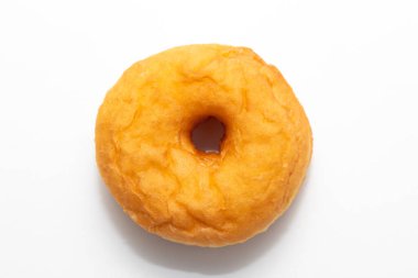 Altın kızartılmış donut, mükemmel yuvarlak, ortasında bir delik, temiz beyaz bir zemin üzerinde sunulur.