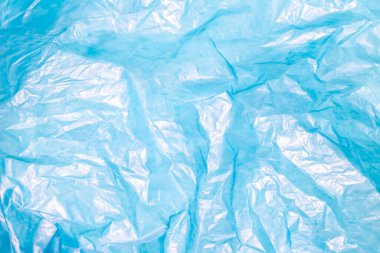 Kırışık bir açık mavi plastik torba, röfleli ve gölgeli desenli, soyut bir arkaplan yaratır..
