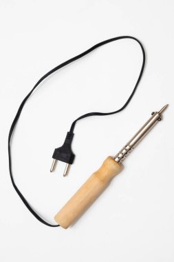 Ahşap saplı lehim demiri, siyah kablosu ve beyaz bir yüzeyde duran iki uçlu dolgusu..