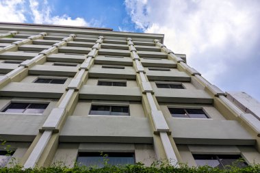 Tekrarlayan pencereleri ve berrak gökyüzü olan çağdaş mimariyi gösteren modern bir binanın düşük açılı görüntüsü.