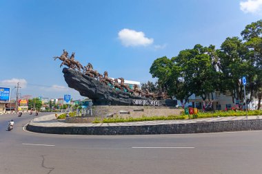 Kayalık bir üste at arabası çeken atları gösteren dinamik bir heykel.