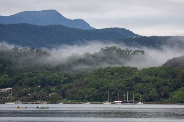 Beautiful view to foggy weather clouds over green rainforest mountains on ocean town, Paraty, Rio de Janeiro, Brazil
