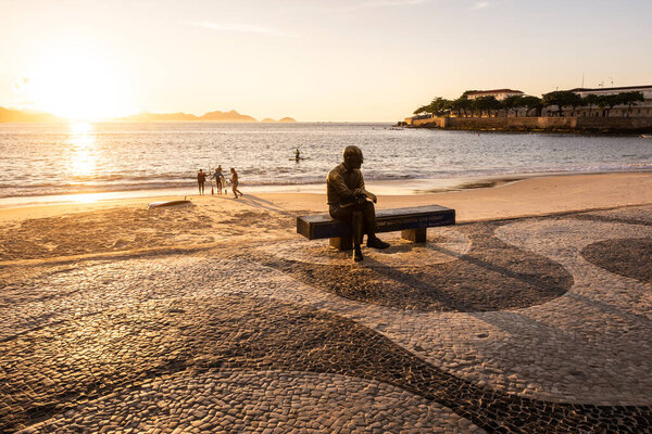 Beautiful sunrise view to poet statue sitting on beach bench in Copacabana, Rio de Janeiro, Brazil