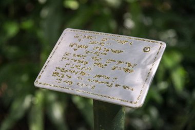 Yeşil yağmur ormanları Tijuca Parkı, Rio de Janeiro, Brezilya 'daki kör ziyaretçiler için körler alfabesiyle yazılmış metal işareti.