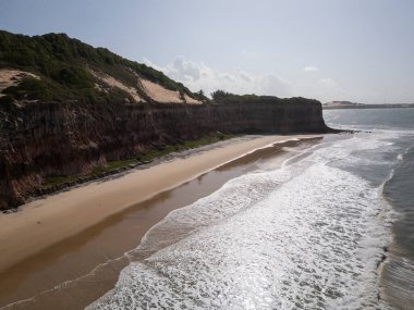 Brezilya 'nın Rio Grande do Norte eyaletinde, Pipa' da turuncu kumlu kayalıkları olan vahşi Baa dos Golfinhos plajının güzel hava manzarası 