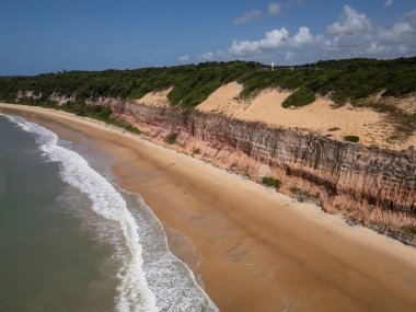 Brezilya 'nın Rio Grande do Norte eyaletinde, Pipa' da turuncu kumlu kayalıkları olan vahşi Baa dos Golfinhos plajının güzel hava manzarası 