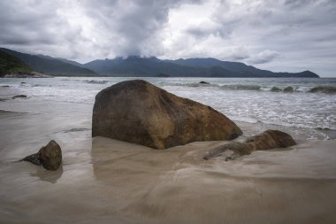 Plaj kayaları, dağlar ve Aventureiro Plajı 'ndaki ağır bulutlar, Ilha Grande, Rio de Janeiro, Brezilya