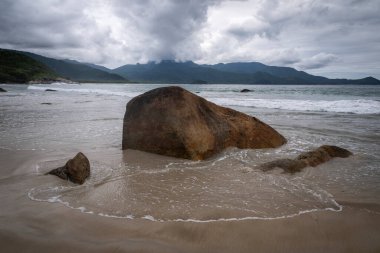 Plaj kayaları, dağlar ve Aventureiro Plajı 'ndaki ağır bulutlar, Ilha Grande, Rio de Janeiro, Brezilya