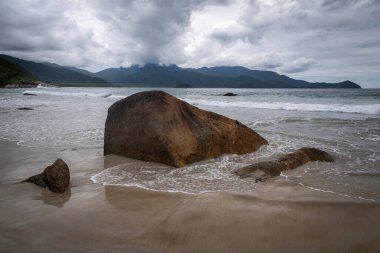 Plaj kayaları, dağlar ve Aventureiro Plajı 'ndaki ağır bulutlar, Ilha Grande, Rio de Janeiro, Brezilya