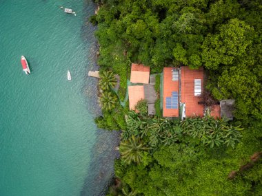 Okyanus üzerindeki yeşil yağmur ormanları için güzel bir hava manzarası küçük ahşap iskelede teknesi olan Ilha Grande, Rio de Janeiro, Brezilya