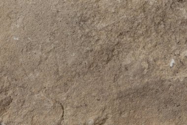 Topraksı kahverengi tonlara ve doğal doku detaylarına sahip engebeli bir taş yüzey, organik veya kırsal temalı tasarımlarda kullanılmak için idealdir..