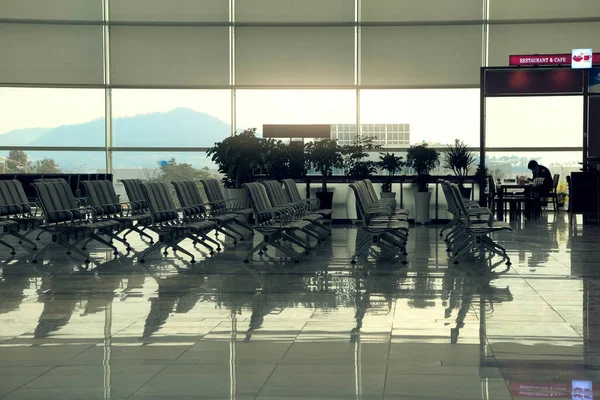 コントロール タワーと日没で離陸する航空機の空港の出発ホールの空の椅子 旅行および交通機関の概念 — ストック写真