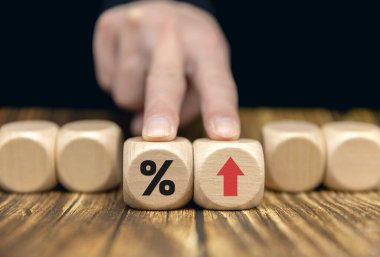 The entrepreneur is holding a block of wood with a percentage and an up arrow. a mortgage rate Interest rates, stocks, rankings, business and financial concepts.