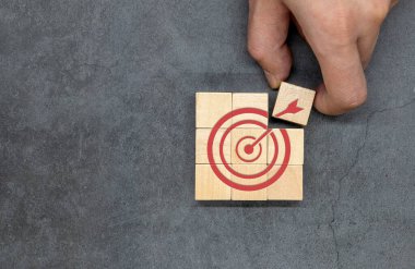 A dart target aiming icon on a wooden cube. Business objectives and concepts of success. Focus on your goals and achieve successful business.