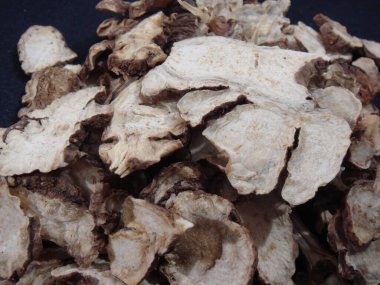 Bütün ve dilimlenmiş Cnidium officinale 'in makro görüntüsü, buruşuk yüzeyi ve lifli iç yüzünü gösteriyor. Geleneksel Asya tıbbında kullanılır.