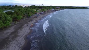 Deniz kenarında güneşli bir günde sahile gidenlerin görüntüsü.