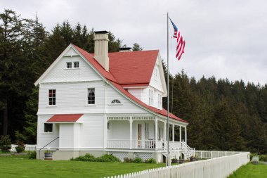 Oregon 'un Pasifik Sahil Otobanı boyunca görkemli bir şekilde tünemiş ikonik bir deniz feneri ve tarihi bekçisinin evi manzaranın simgesi olarak duruyor. Engebeli sahil kayalıkları arasında panoramik okyanus manzaraları sunuyor..
