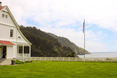Oregon 'un Pasifik Sahil Otobanı boyunca görkemli bir şekilde tünemiş ikonik bir deniz feneri ve tarihi bekçisinin evi manzaranın simgesi olarak duruyor. Engebeli sahil kayalıkları arasında panoramik okyanus manzaraları sunuyor..