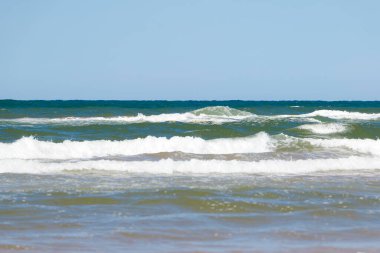 Yaz mevsiminde kumlu sahilde yumuşak bir mavi okyanus dalgası. Prens Edward Adası, Kanada