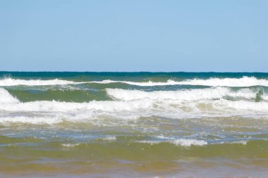 Yaz mevsiminde kumlu sahilde yumuşak bir mavi okyanus dalgası. Prens Edward Adası, Kanada