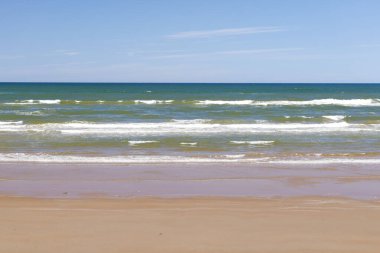 Yaz mevsiminde kumlu sahilde yumuşak bir mavi okyanus dalgası. Prens Edward Adası, Kanada