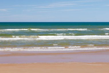 Yaz mevsiminde kumlu sahilde yumuşak bir mavi okyanus dalgası. Prens Edward Adası, Kanada