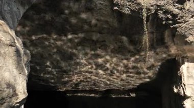 Su dalgaları ışıkla parıldayan dev bir kayayı nazikçe yansıtır. Yüksek kalite 4k görüntü