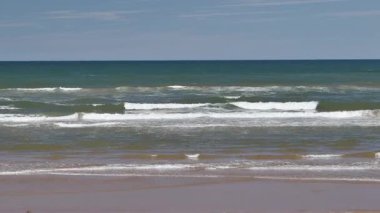 Yaz mevsiminde kumlu sahilde yumuşak bir mavi okyanus dalgası. Prens Edward Adası, Kanada