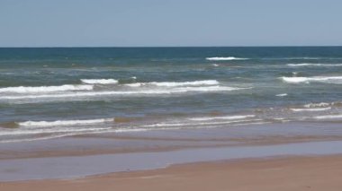 Yaz mevsiminde kumlu sahilde yumuşak bir mavi okyanus dalgası. Prens Edward Adası, Kanada