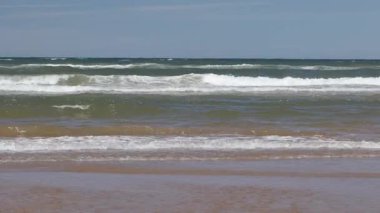 Yaz mevsiminde kumlu sahilde yumuşak bir mavi okyanus dalgası. Prens Edward Adası, Kanada