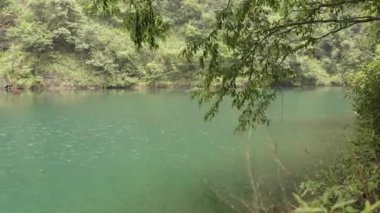 Yağmur damlaları yağmurlu bir yaz gününde sakin mavi bir gölette dalgalı desenler oluşturur. Yüksek kalite 4k görüntü