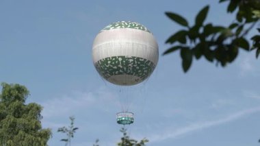 Sıcak hava balonu ön planda yapraklarla havada uçuyor. Yüksek kalite 4k görüntü