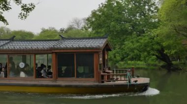 Hangzhou 'daki Batı Gölü' nde yüzen tahta tekneler büyüleyici doğal manzarayla çevrili. Yüksek kalite 4k görüntü