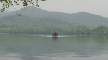 Hangzhou 'daki Batı Gölü' nde yüzen tahta tekneler büyüleyici doğal manzarayla çevrili. Yüksek kalite 4k görüntü